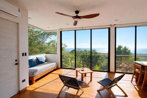 Ein geräumiger Balkon mit Holzboden, einer Couch mit Kissen, zwei Stühlen und einem Tisch.