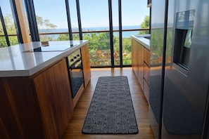 Eine moderne Küche mit einer Holzausziehtheke, einem eingebauten Kühlschrank und Meerblick.