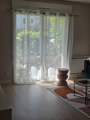A room with a large sliding glass door, a round table, and a chair. - A beautiful, cozy apartment (La Chapelle-sur-Erdre)