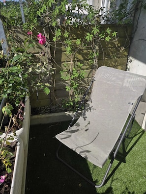 Ein Garten mit einem Metallstuhl, einem Holzzaun und einer Mauer.