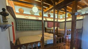 Quarto com escada de madeira, cama, um banco e teto decorativo.
