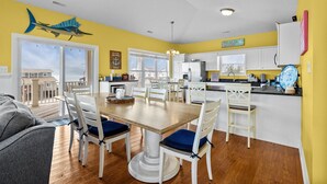 A bright kitchen with white cabinets, a wooden dining table, and a view to the outside.