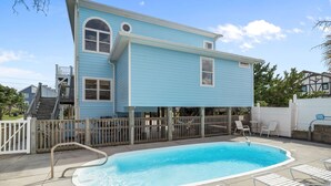A two-story house with a swimming pool, a wooden deck, and a fenced patio area.