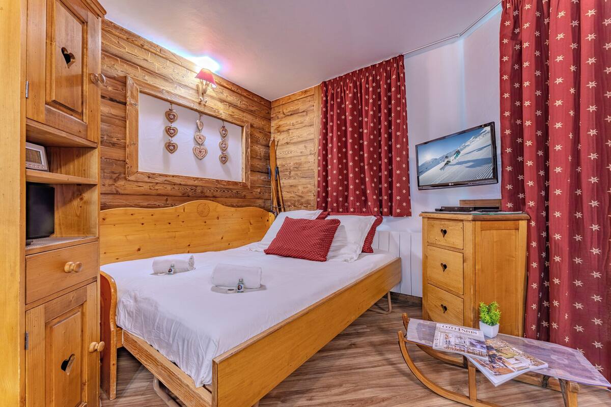 Une pièce en bois avec un lit, une télévision et un journal sur une table.