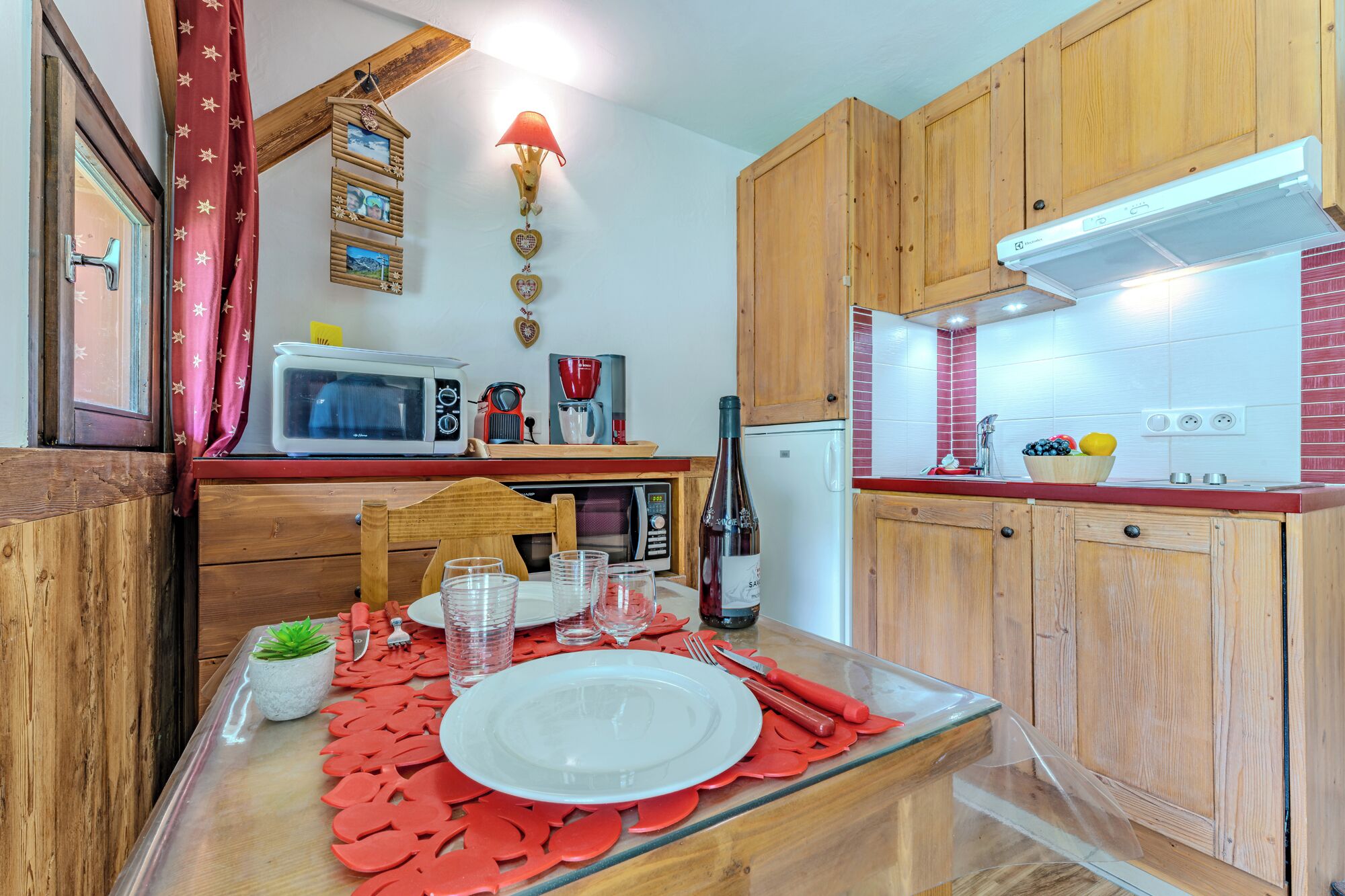 Una cocina compacta con armarios de madera, microondas, cafetera y refrigerador.