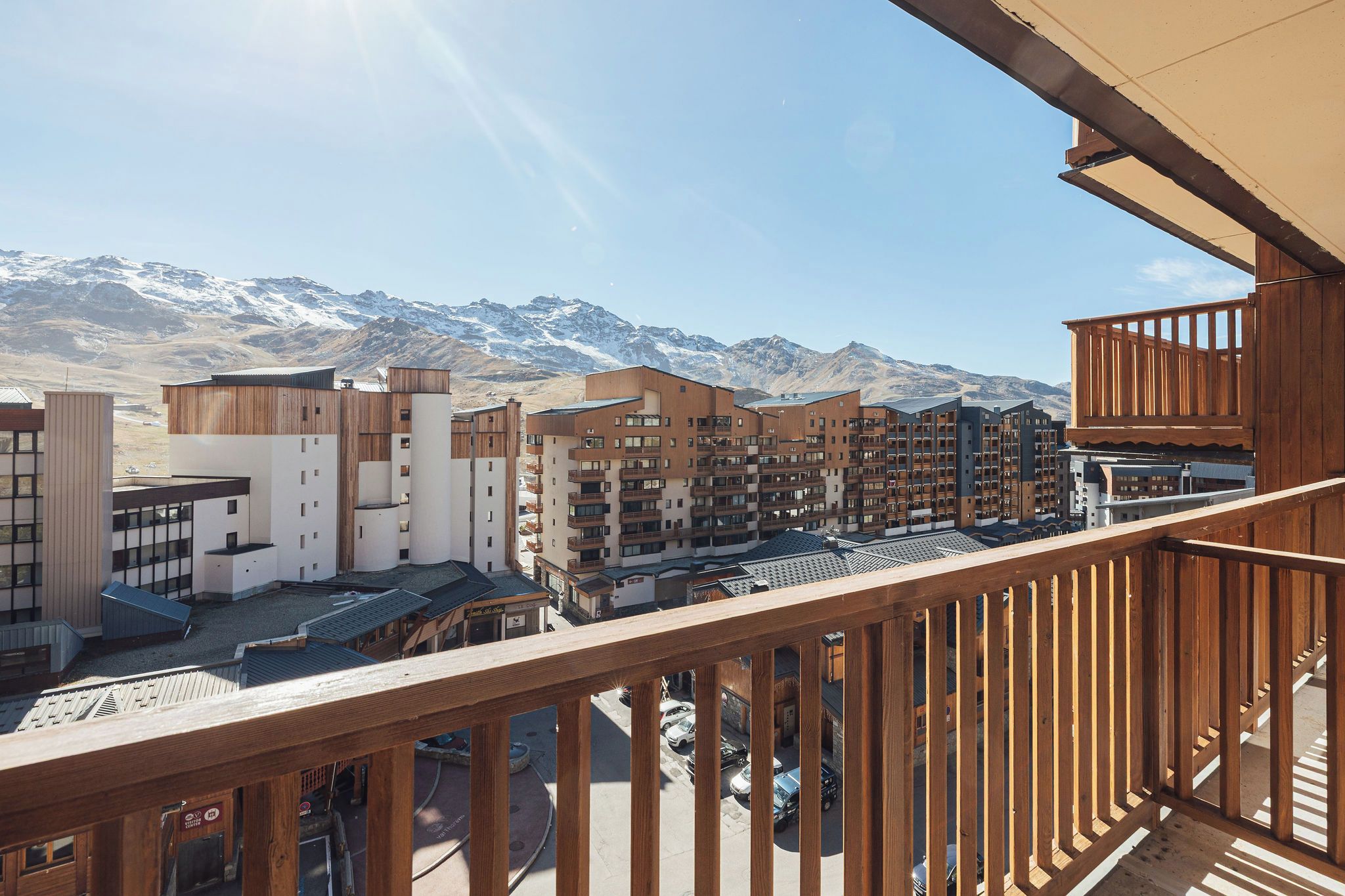 Un hotel de varios pisos, con balcones y vistas a montañas nevadas.