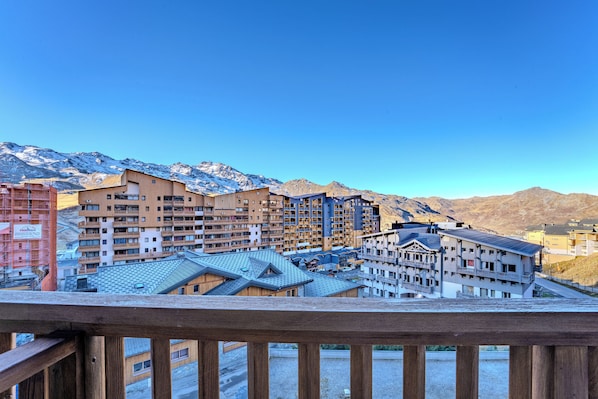 A resort area with multiple buildings, a wooden deck, and mountains in the background.