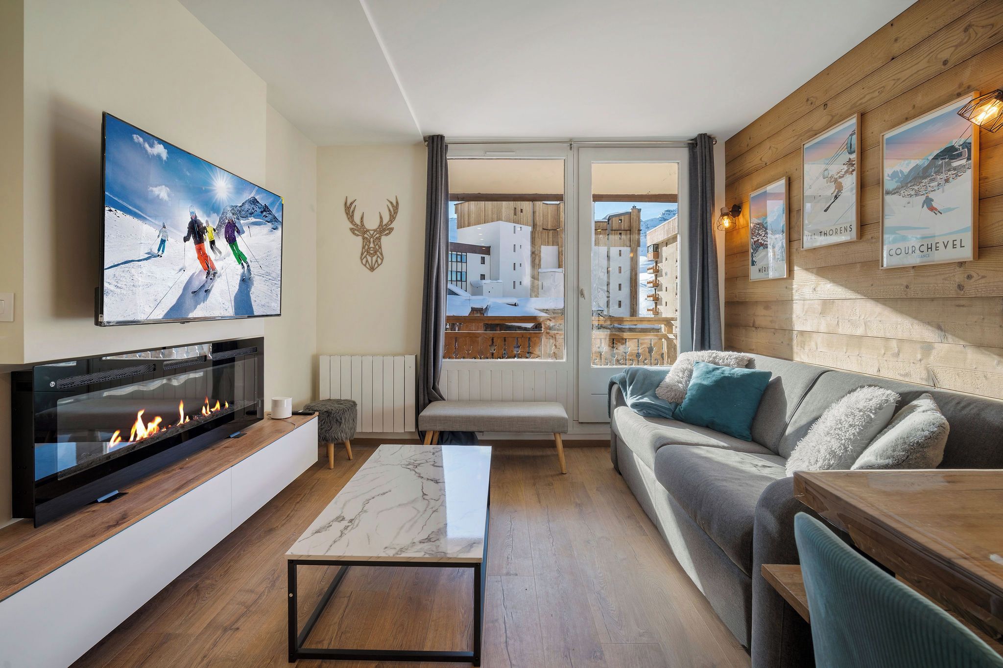 A modern living room with a fireplace, a sofa, a coffee table, and a television mounted on the wall.