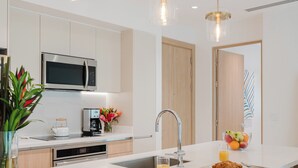 Cozinha moderna com ilha central, eletrodomésticos de aço inoxidável e iluminação pendente.