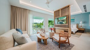 Quarto de hotel moderno com varanda, televisão, cama, sofá e área de jantar.