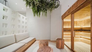 Um interior moderno com sofá branco, bancos de madeira, planta pendente e área com bancos de madeira.