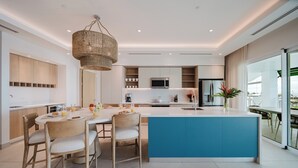 A modern kitchen with a central island, built-in appliances, and a dining area with chairs. - Step Into Unparalleled Luxury and Expansive Comfort at our Signature Residences (Quepos)