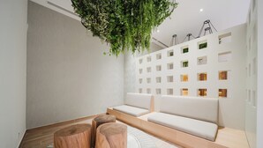A modern interior with a seating area, wooden stools, a hanging plant, and a wall with multiple small windows. - Step Into Unparalleled Luxury and Expansive Comfort at our Signature Residences (Quepos)