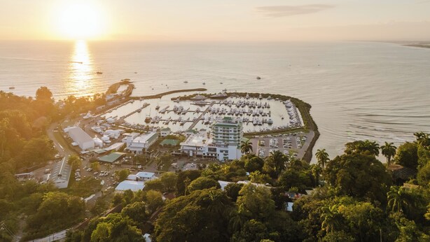 An aerial view of a marina with boats docked, surrounded by greenery and buildings. - Step Into Unparalleled Luxury and Expansive Comfort at our Signature Residences (Quepos)
