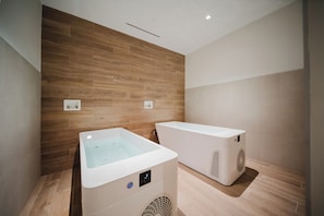 A modern bathroom with a wooden wall, a bathtub, and a sauna unit. - Discover Unparalleled Elegance at our Marina Vista Villas! (Telire)