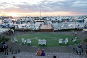 Un puerto deportivo con barcos amarrados, una zona verde con sillas y una terraza de madera.