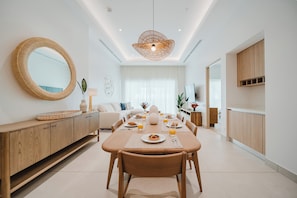A modern dining area with a round mirror, wooden furniture, and a central table with breakfast items.