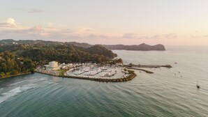 An aerial view of a marina with boats docked, surrounded by hills and a clear sky. - Discover the Pinnacle of Luxury and Serenity With La Costa! (Quepos)
