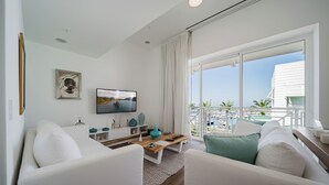 A modern living room with a TV, white sofas, a wooden coffee table, and a balcony with outdoor furniture. - Discover the Pinnacle of Luxury and Serenity With La Costa! (Quepos)