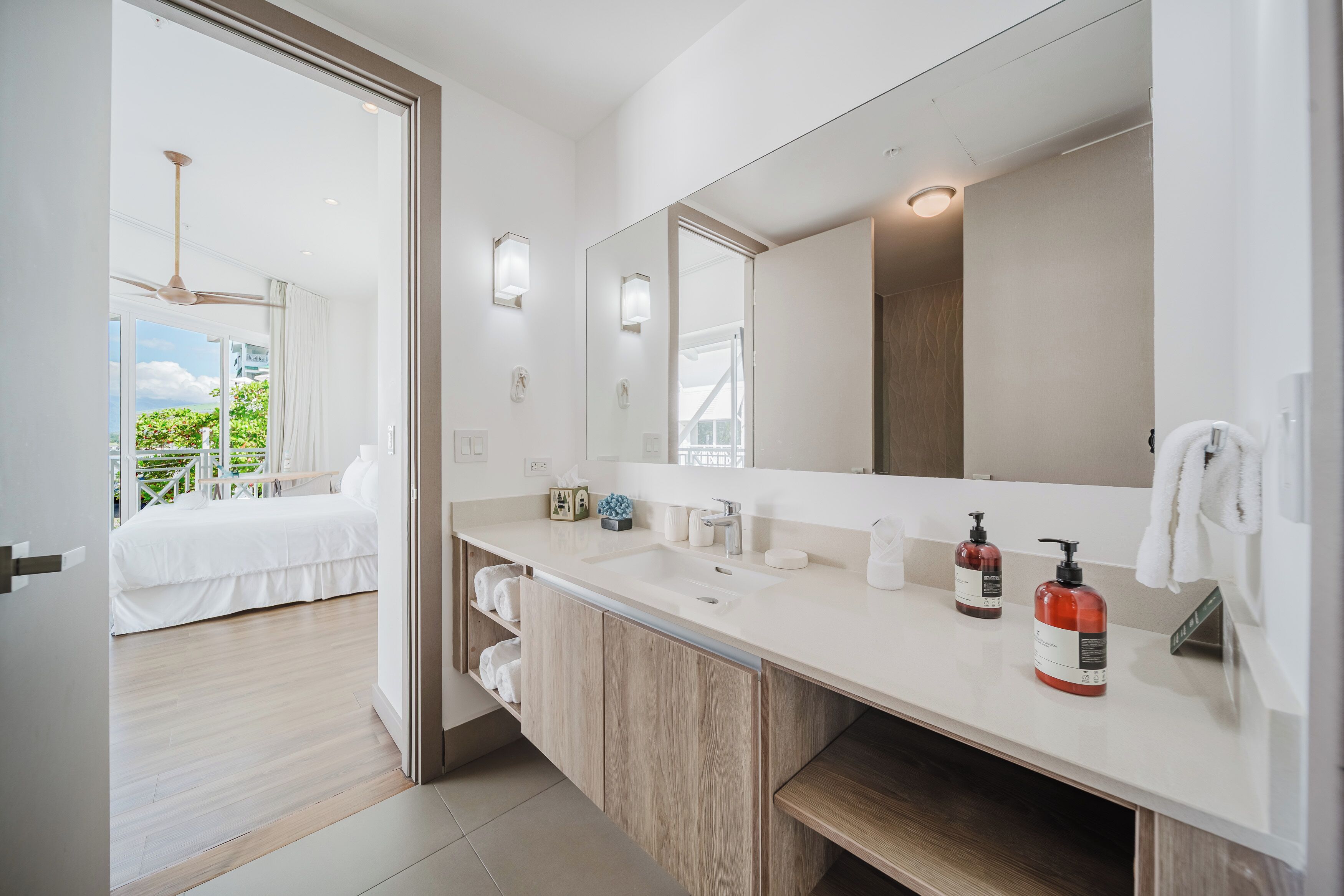 Un baño moderno con un espejo grande, un lavamanos y dos dispensadores de jabón rojos.