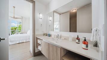 Un baño moderno con un espejo grande, un lavamanos y dos dispensadores de jabón rojos.