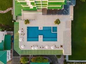 An aerial view of a hotel with a large swimming pool, outdoor seating, and a green roof. - Discover the Pinnacle of Luxury and Serenity With La Costa! (Telire)