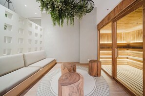 A modern interior with a white sofa, wooden stools, a hanging plant, and a wooden bench area.