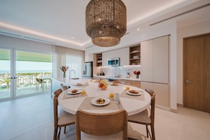 A modern dining area with a round table, chairs, and a central fruit bowl. - Experience Expansive Luxury at our Gran Costa Villas! (Telire)