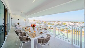 Ein Balkon mit Esstisch, gedeckt für das Frühstück, mit Blick auf einen Yachthafen.