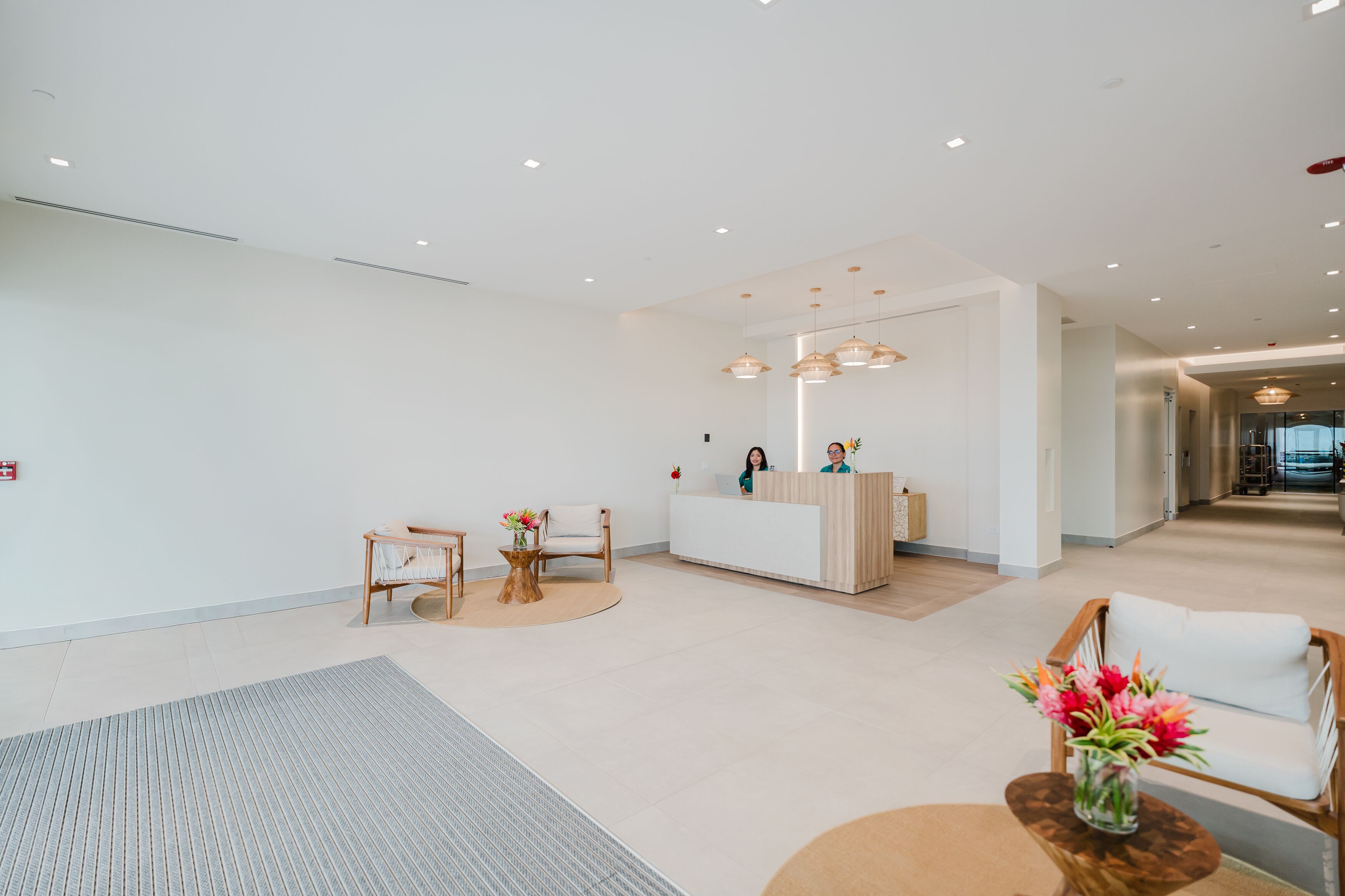 A modern reception area with a reception desk, seating, and a hallway leading to other rooms.