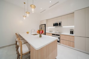 A modern kitchen with a central island, stainless steel appliances, and pendant lighting.