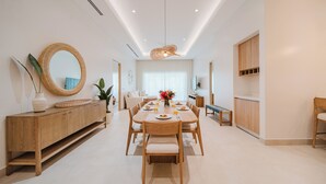 Et moderne spiseområde med et træbord, stole, et buffetbord og et stort spejl.