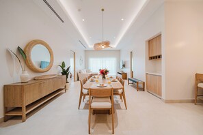A modern dining area with a wooden table, chairs, a buffet, and a large mirror.