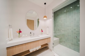 A modern bathroom with a white vanity, a large mirror, and a glass shower enclosure. - Experience the Ultimate in Spacious Luxury at our Panorama Villas! (Telire)
