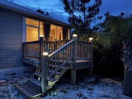 Una terraza de madera con una escalera que conduce a una casa con ventanas grandes.