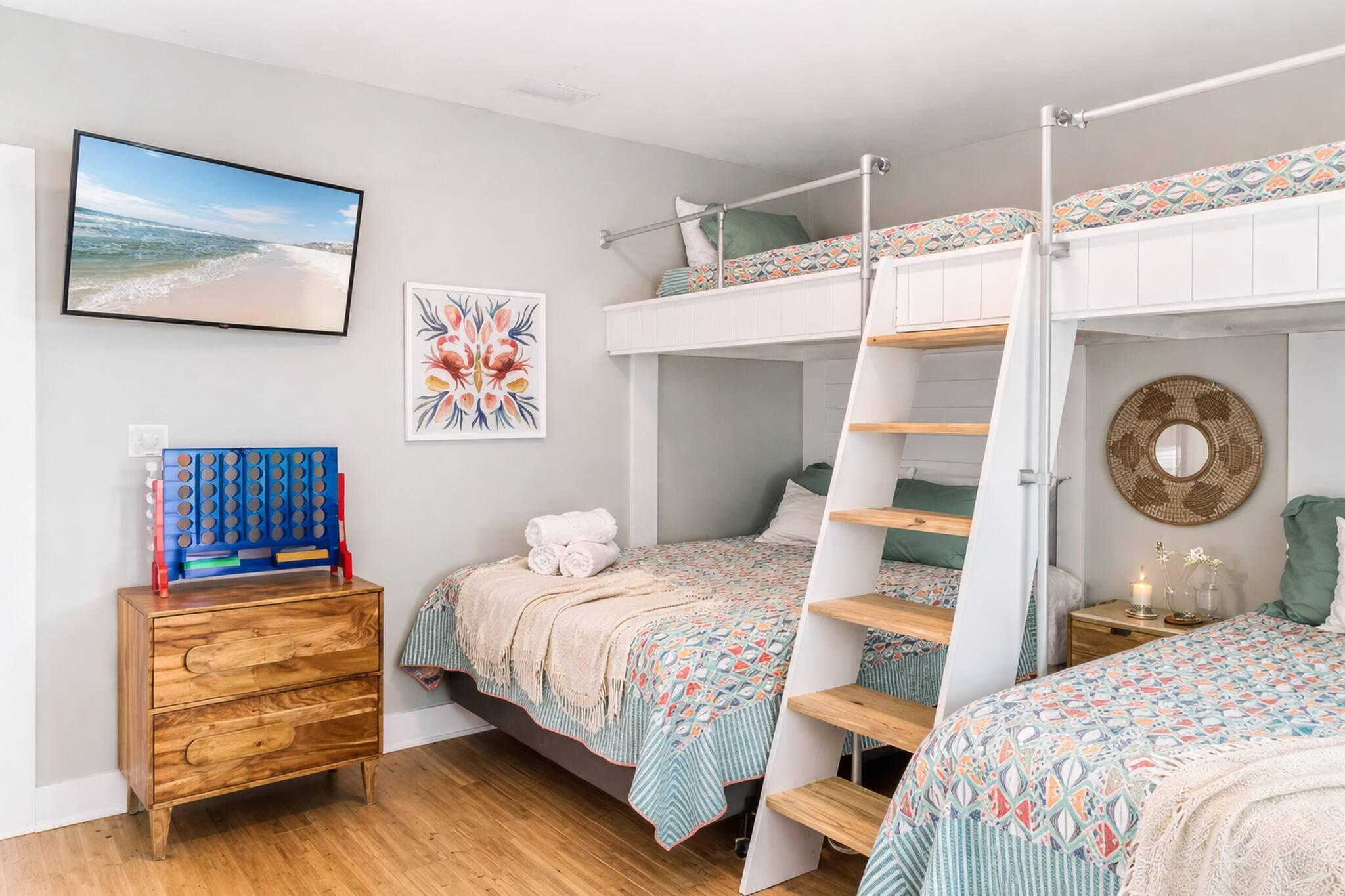 A bedroom with bunk beds, a wooden dresser, a television, and a wall-mounted picture.