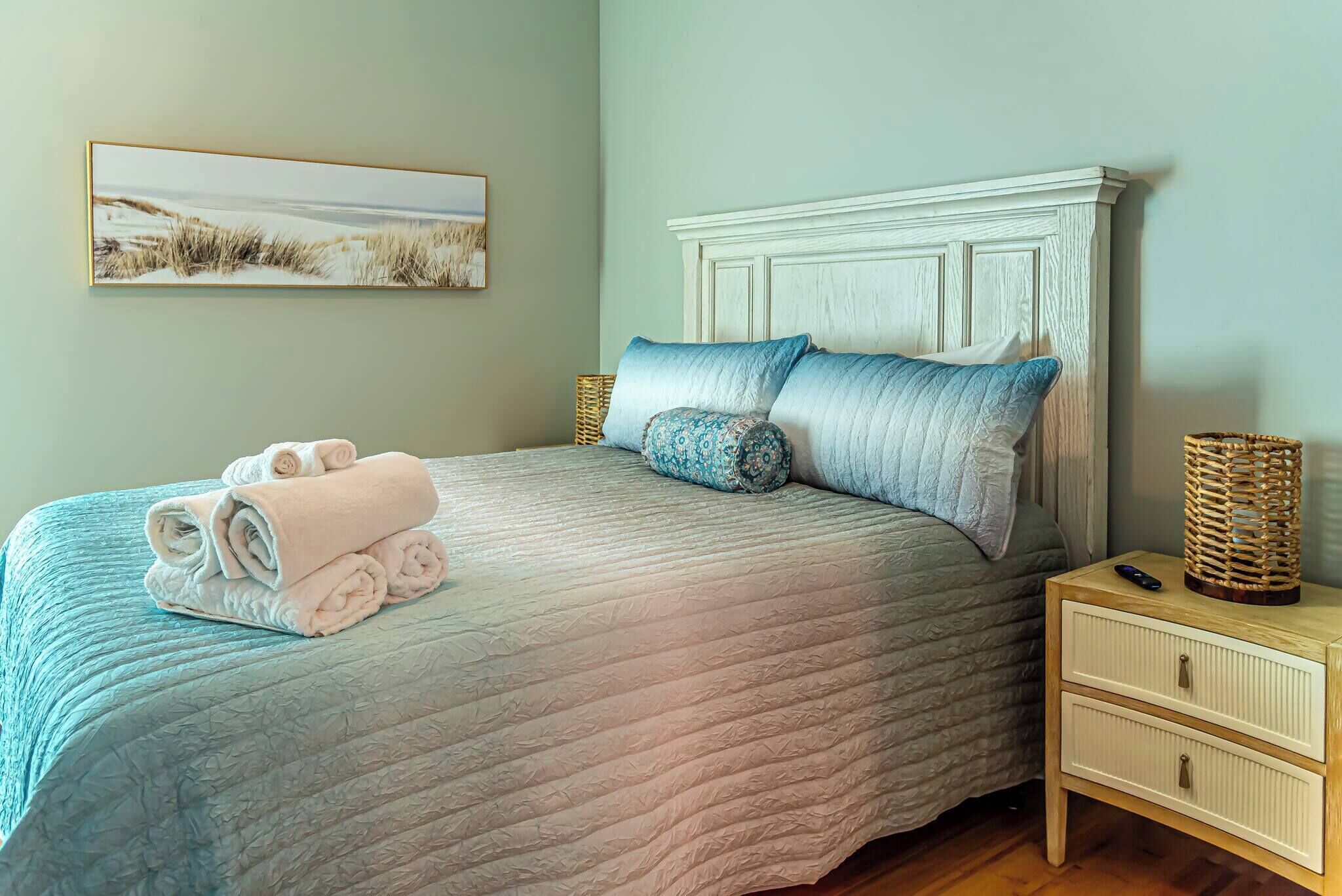A neatly made bed with a quilted cover, a headboard, and decorative pillows.