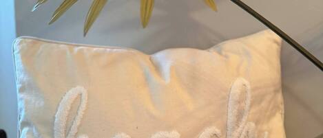 A pillow with the word 'beach' embroidered on it, placed on a wooden surface.