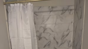 A bathroom with a shower curtain, a bathtub, and marble-patterned walls. - Log Comfort 3 (Newark)