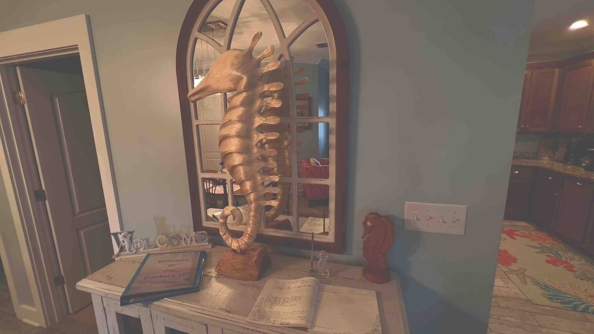 A room with a large mirror, a wooden sculpture, and a welcome sign.