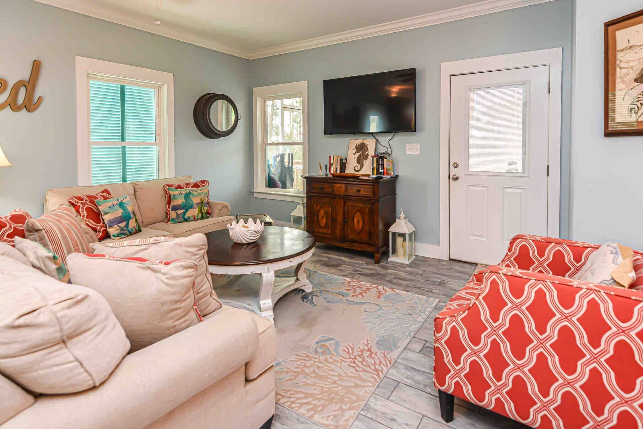 A living room with a sofa, armchair, coffee table, and patterned rug.