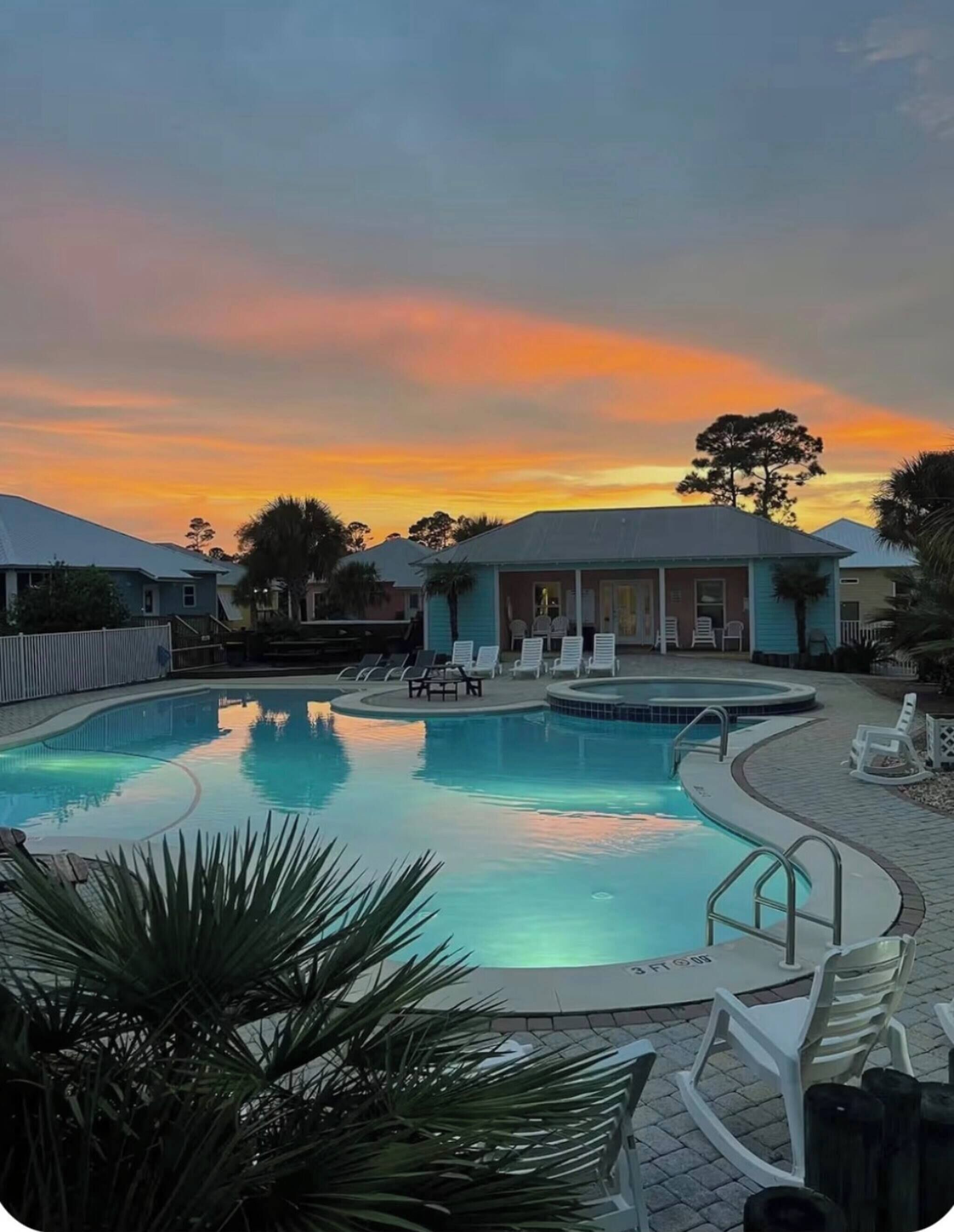 A swimming pool with lounge chairs and a building with a porch.