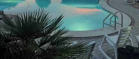 A swimming pool with lounge chairs and a building with a porch.