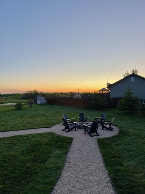 A backyard with a gravel path, outdoor seating, and a house.