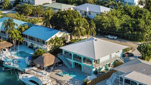 En fastighet vid kusten med en swimmingpool, en brygga och en tvåvåningsbyggnad med en balkong.