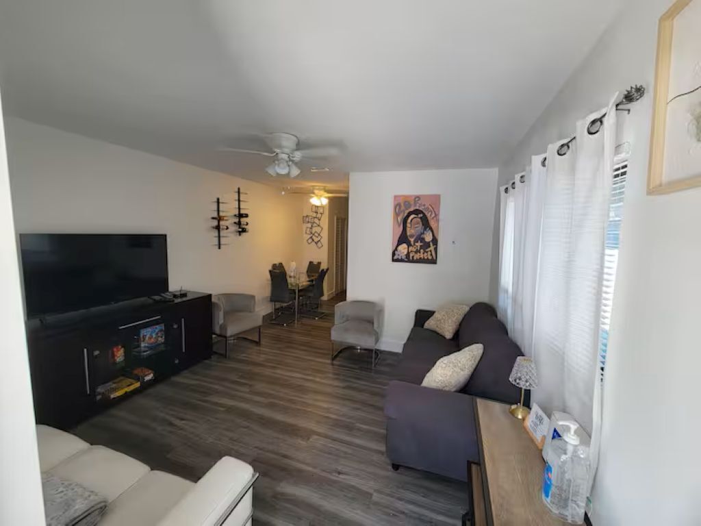 A living room with a TV, sofa, and a dining area with chairs.