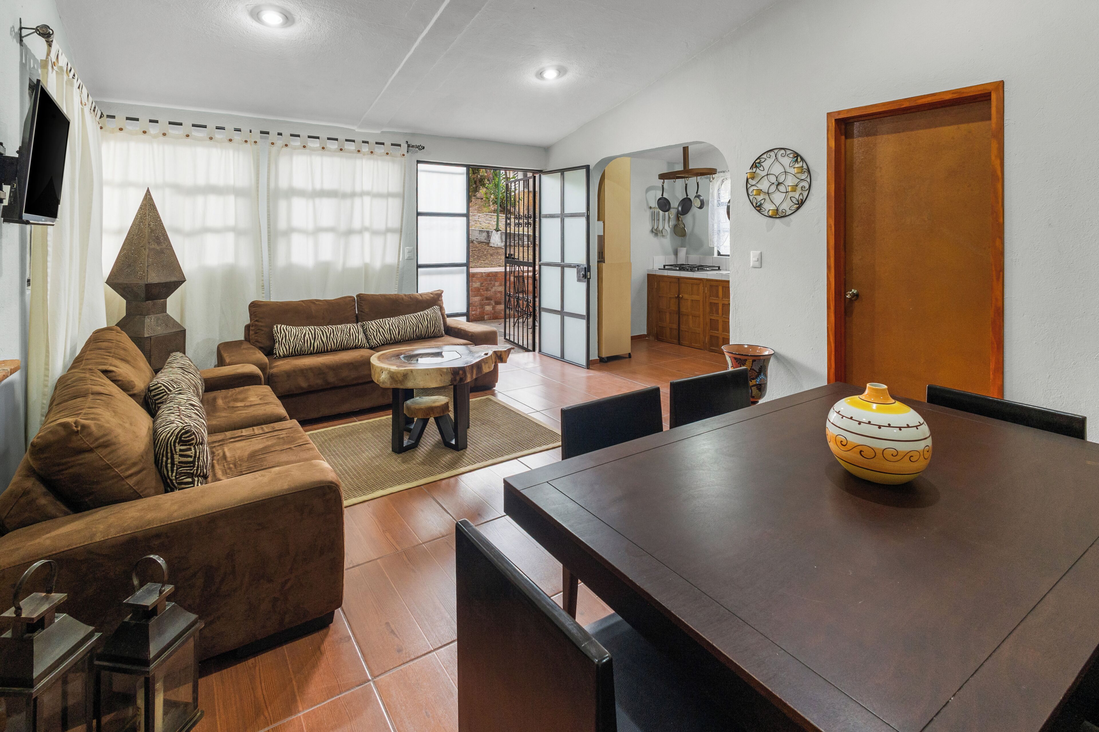 Una sala de estar con un sofá, una mesa de centro y una mesa de comedor con sillas.