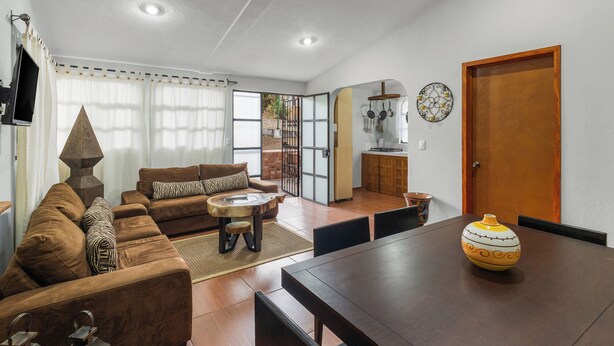Una sala de estar con un sofá, una mesa de centro y una mesa de comedor con sillas.