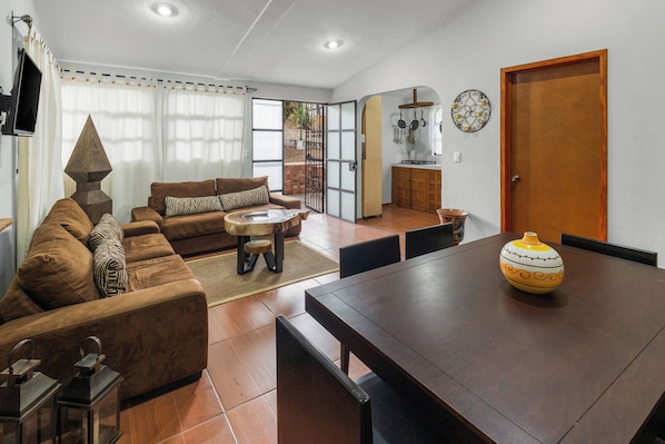 Una sala de estar con un sofá, una mesa de centro y una mesa de comedor con sillas.