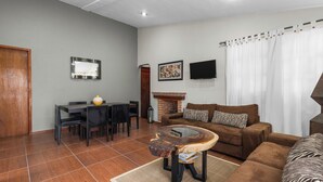 Una sala de estar con sofá, mesa de centro, chimenea, televisión y un comedor con sillas y mesa.